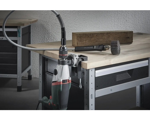 Flexibler Wellenaufsatz mit Bohrmaschine an einer Werkbank befestigt, mit einem Holzstück und Bürstenaufsatz