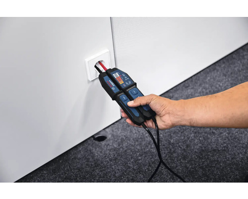 Main tenant un testeur de tension bipolaire Bosch dans une prise de courant