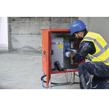 Électricien travaillant sur un poste de distribution électrique sur un chantier.