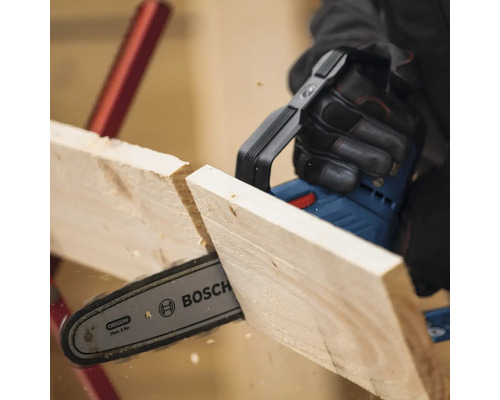 Une personne scie une planche de bois avec une tronçonneuse sans fil. Logo Bosch.