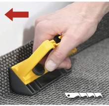 Eine Person schneidet einen Teppich mit einem Teppichschneider.
