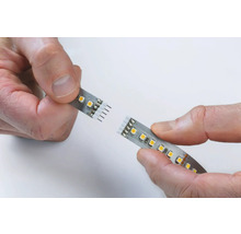 Zwei LED-Streifen werden von Händen zusammengehalten.