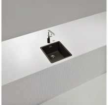 Évier de cuisine foncé avec robinet sur un plan de travail blanc.