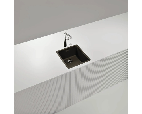 Évier de cuisine foncé avec robinet sur un plan de travail blanc.