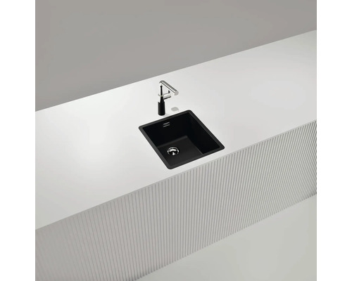 Schwarze Küchenspüle mit Armatur auf einer weißen Arbeitsplatte