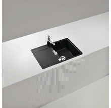 Schwarze Küchenspüle mit Abtropffläche und Armatur auf einer Arbeitsplatte.