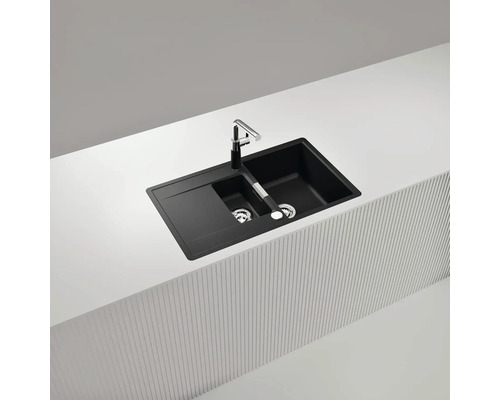 Schwarze Küchenspüle mit Abtropffläche und Armatur auf einer Arbeitsplatte