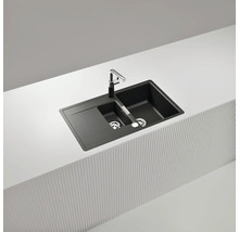 Schwarze Doppelspüle mit Abtropffläche und Armatur auf einer Küchenarbeitsplatte.