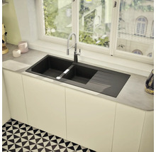 Évier de cuisine noir avec égouttoir et robinet devant une fenêtre