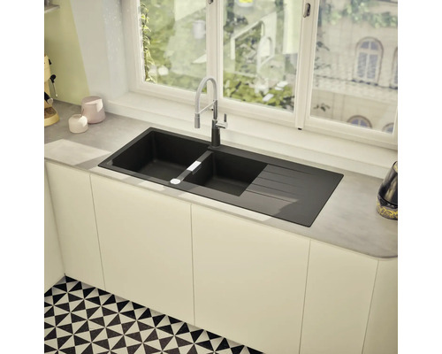 Évier de cuisine noir avec égouttoir et robinet devant une fenêtre