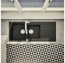 Évier de cuisine noir avec égouttoir, robinetterie et carrelage à motifs.