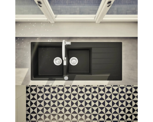 Évier de cuisine noir avec égouttoir, robinetterie et carrelage à motifs.