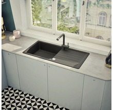 Schwarzes Spülbecken mit Abtropffläche und Wasserhahn in einer modernen Küche.