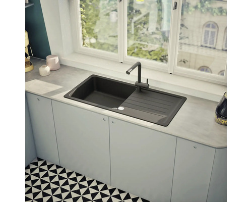 Schwarzes Spülbecken mit Abtropffläche und Wasserhahn in einer modernen Küche.