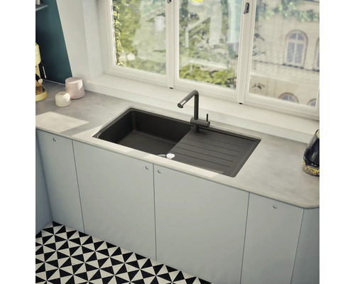 Spüle mit Abtropffläche und Armatur in einer hellen Küche vor einem Fenster