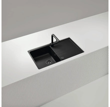 Schwarze Küchenspüle mit Abtropffläche und Armatur in einer hellen Arbeitsplatte