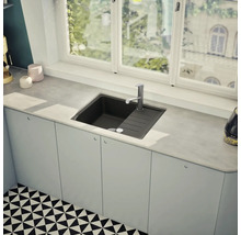 Spüle aus Stein mit Abtropffläche und Einhebelmischer in einer hellen Küche