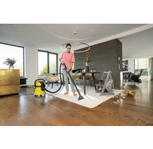 Femme nettoie un tapis avec un aspirateur-laveur dans un salon