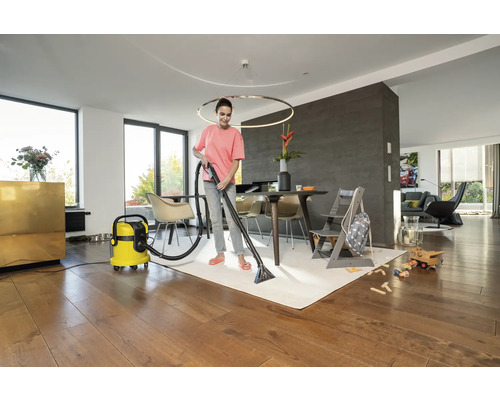 Femme nettoie un tapis avec un aspirateur-laveur dans un salon