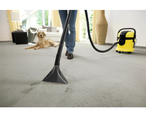 Personne nettoyant un tapis avec un injecteur extracteur dans un environnement de vie lumineux