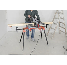 Eine Person bedient eine Kappsäge auf einem Sägetisch, neben einer Leiter.