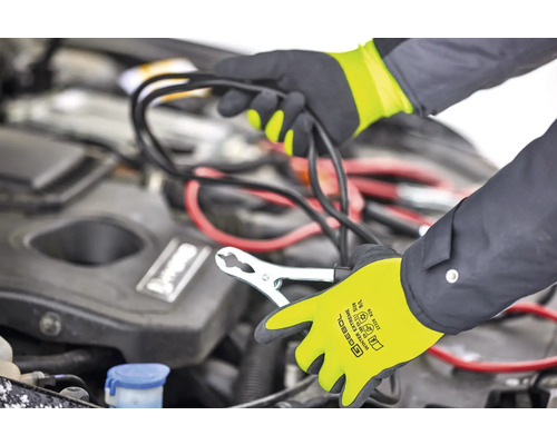 Eine Person schliesst mit Überbrückungskabeln eine Autobatterie an, wobei sie Handschuhe trägt.