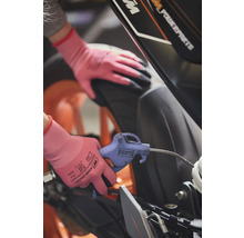 Une personne nettoie une moto avec une soufflette et des gants de protection.