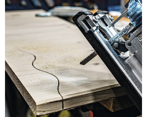 Gros plan d''une scie sauteuse coupant un motif incurvé dans une planche de bois