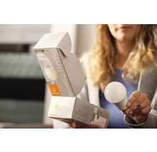 Frau hält eine intelligente Glühbirne mit Verpackung