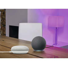 Szene mit einem intelligenten Lautsprecher und einem Smart Home Gerät auf einem Holztisch