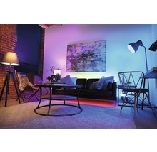 Wohnzimmer mit Sofa, Tisch, Stehlampe und farbiger Beleuchtung für eine angenehme Atmosphäre