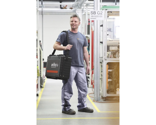 Mann trägt Werkzeugkoffer von Wiha in einer Produktionshalle