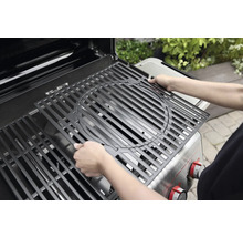 Une personne installe une grille de cuisson dans un barbecue à gaz.