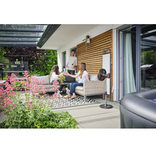 Terrasse avec mobilier de salon, ventilateur sur pied et personnes détendues