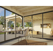 Pièce lumineuse avec plafond en bois, grandes fenêtres et vue sur une terrasse avec mobilier de jardin