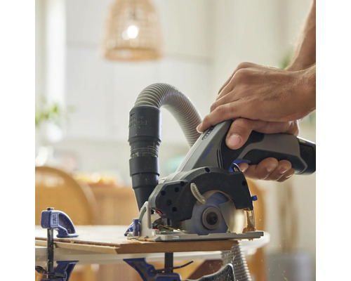 Un homme scie du bois avec une scie plongeante avec aspiration de poussière