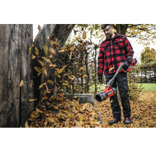 Homme avec souffleur de feuilles à batterie dans le jardin soufflant les feuilles