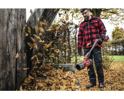 Homme avec souffleur de feuilles à batterie dans le jardin soufflant les feuilles