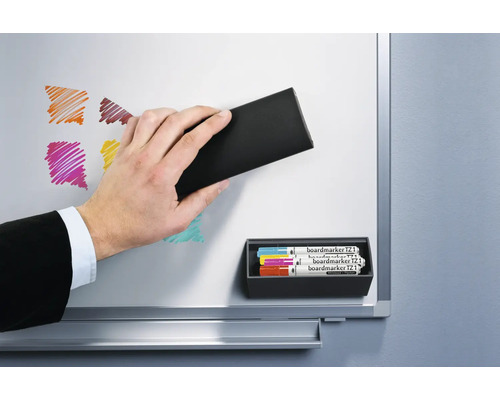 Hand wischt mit einem Tafellöscher eine Magnettafel sauber. Tafelmarker sind in einem Halter befestigt.
