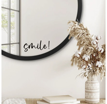 Intérieur décoratif avec miroir rond, inscription 'smile', graminées ornementales et vase à motifs.