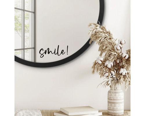 Dekoratives Interieur mit rundem Spiegel, Schriftzug 'smile', Ziergras und gemusterter Vase.