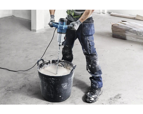 Artisan mélangeant du matériau avec un mélangeur à mortier dans un seau.