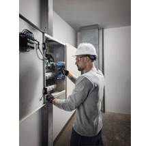Électricien travaillant avec une visseuse sans fil sur une boîte de distribution.