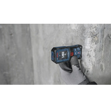 Télémètre laser mesurant sur un mur gris