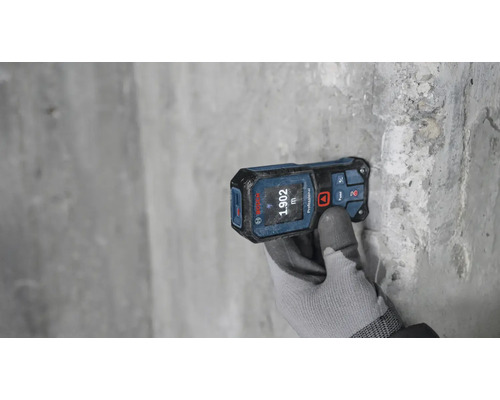 Télémètre laser mesurant sur un mur gris