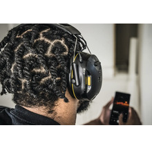 Personne portant un casque antibruit 3M et utilisant un téléphone portable.