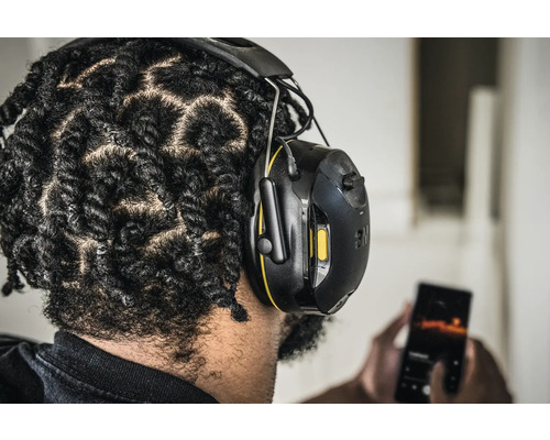 Personne portant un casque antibruit 3M et utilisant un téléphone portable.