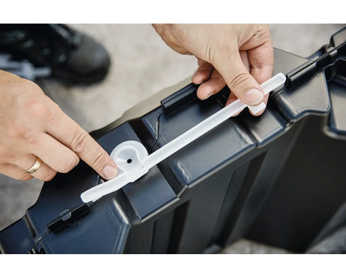 Une personne fixe un joint sur une boîte de rangement en plastique.