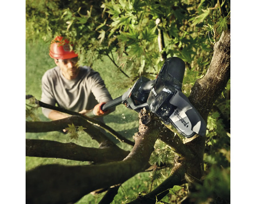 Un homme coupe une branche avec une tronçonneuse à batterie Husqvarna