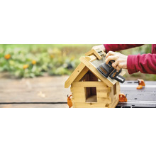 Eine Person schleift ein Vogelhaus mit einem Schwingschleifer der Marke WORX.
